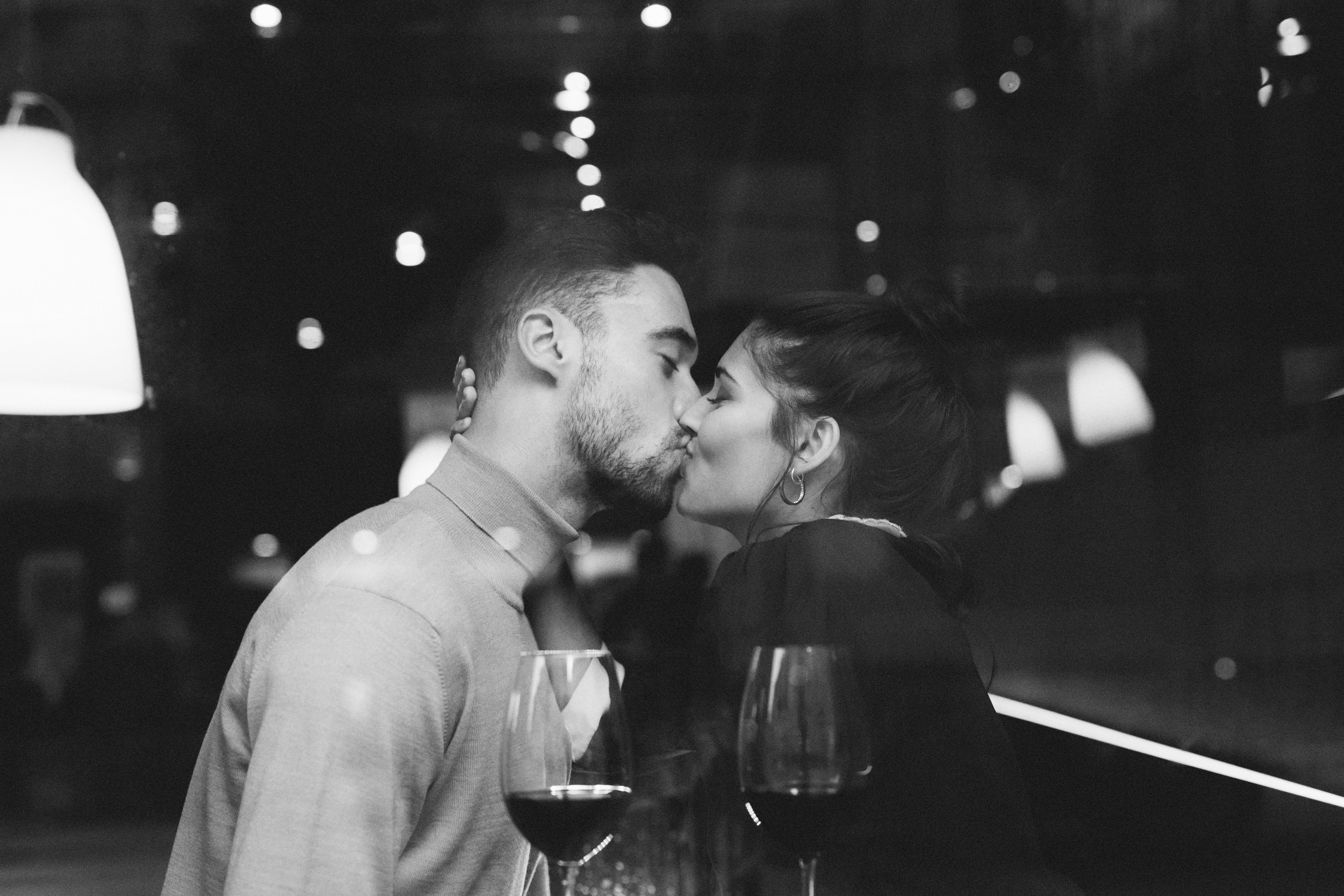 man-kissing-woman-near-glasses-wine-restaurant